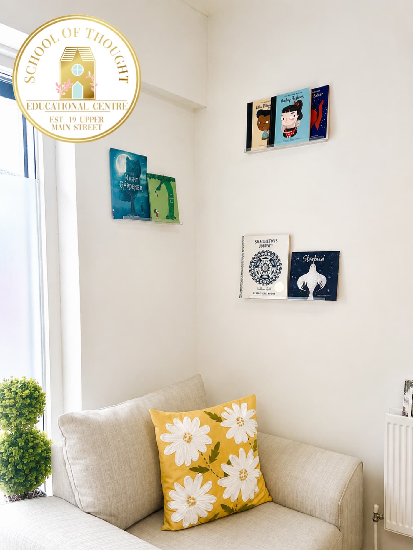 The cosy reading corner at School of Thought NI, with a sofa, daisy cushion and bookshelves